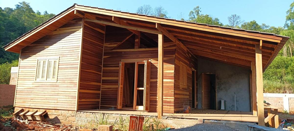 Vista frontal da residência pré-fabricada de madeira com varanda e abrigo