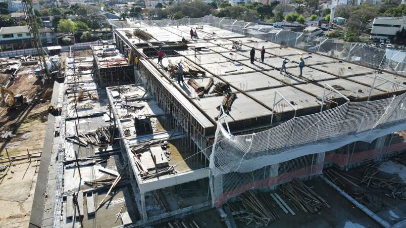 Vista aérea de obra lindeira em estrutura de concreto, ao lado do terreno do novo hospital