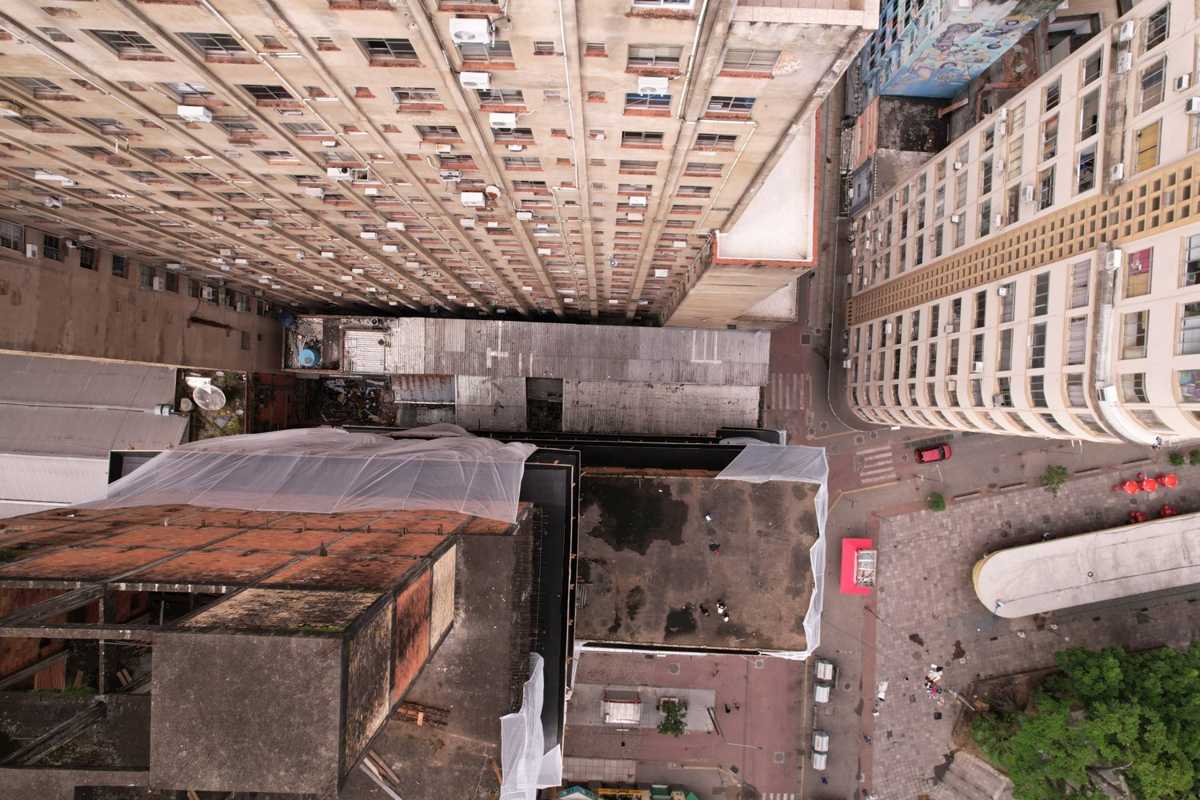 Vista zenital de edifícios altos e de prédio com tela de proteção, registrada com drone