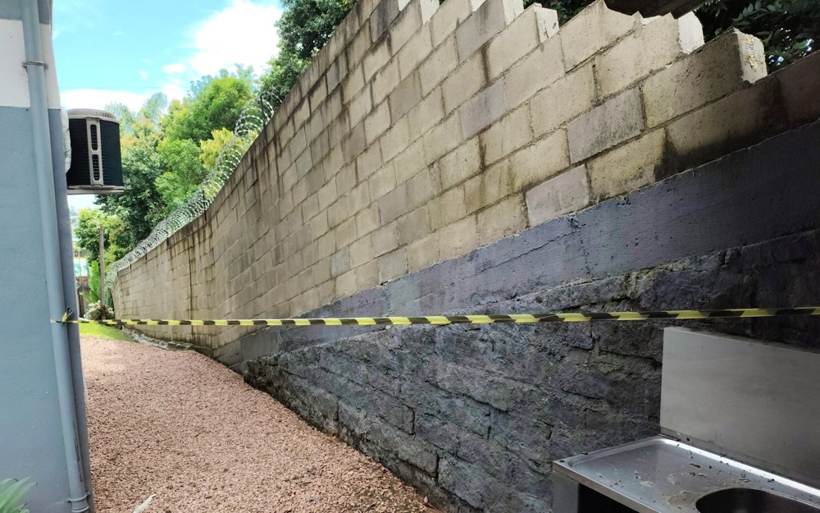 Trecho remanescente do muro isolado com fita zebrada