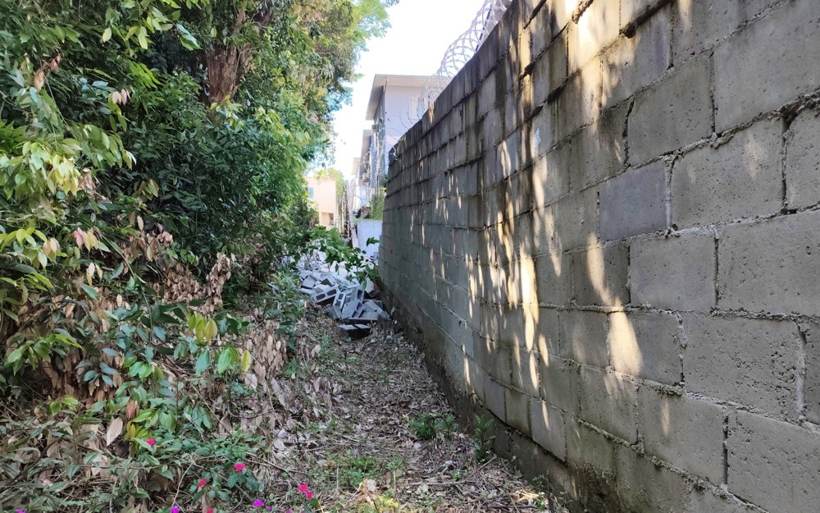 Face externa do muro de blocos de concreto ainda em pé, com blocos caídos ao fundo